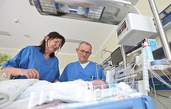 Krankenschwester und Arzt beugen sich über Babybett auf der Kinderintensivstation